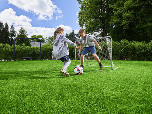 Kids playing with a football on grass. Link to the webpage roots under lawns